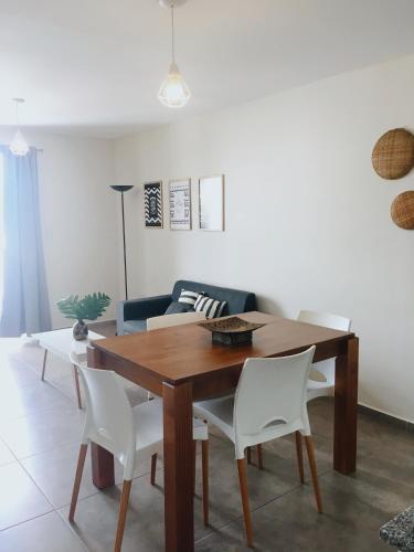 sala de estar con mesa de madera y sillas blancas en Departamento amplio con balcón y bella vista en Salta