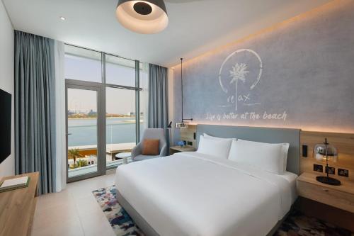 a bedroom with a bed and a desk and a window at NH Collection Dubai The Palm in Dubai