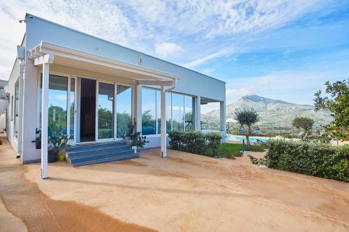 a blue house with a porch with mountains in the background at Villa Mayas - Scopello in Castellammare del Golfo