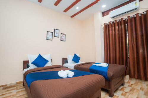 - une chambre dotée de 2 lits avec des draps bleus et bruns dans l'établissement Dubori Homestay, à Guwahati