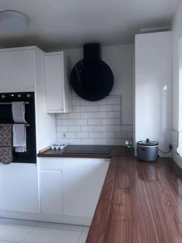 a kitchen with white cabinets and a wooden floor at Home in Basildon, Essex in Basildon