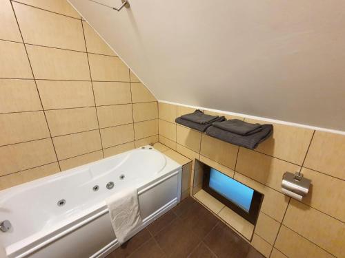 uma casa de banho com banheira e 2 toalhas pretas em Pensiunea Nossa Panzió em Corunca