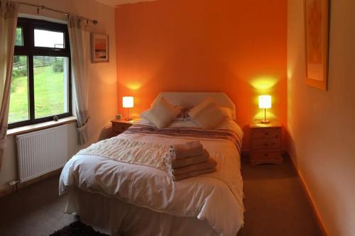 a bedroom with a bed with two lamps and a window at Snowberry Cottage No 2 in Onich
