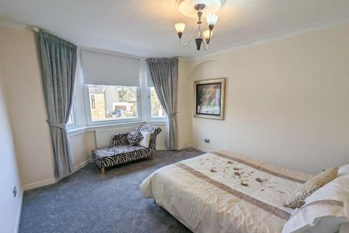 a bedroom with a bed and a couch and a window at The Old High Road in Stevenston