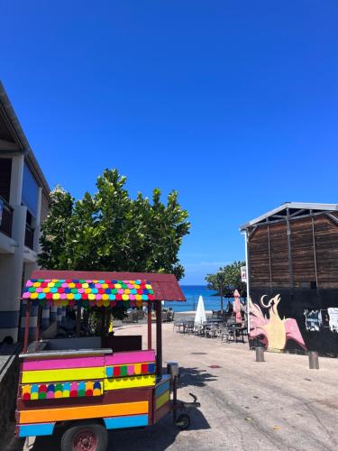 a colorful cart parked on a beach with the ocean in the background at Studio bord de mer in Filaos