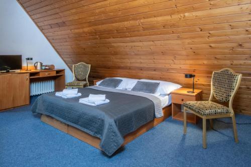 a bedroom with a bed and two chairs and a television at Wellness Hotel Šedý Vlk in Harrachov