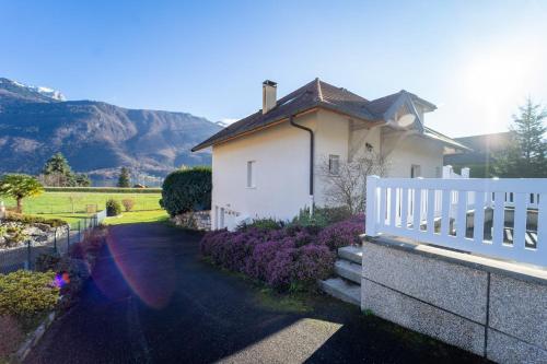 a white house with a fence and a driveway at Entre lac et montagnes in Doussard