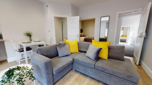 ein Wohnzimmer mit einem grauen Sofa und gelben Kissen in der Unterkunft 1 Castle Yard in Coventry