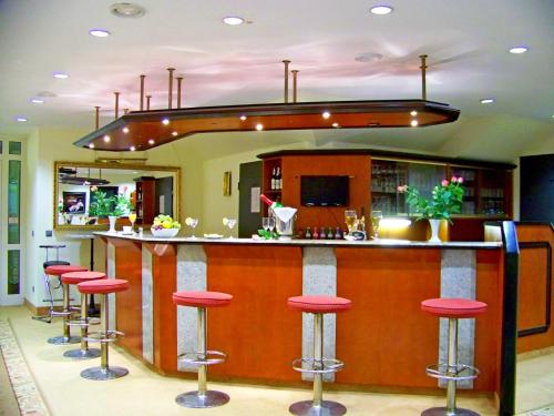 a bar with red stools in a room at Hotel Amadeus ROYAL Berlin in Berlin