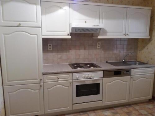 uma cozinha com armários brancos e um forno com placa de fogão em Le Berceau des Croisades em Bouillon