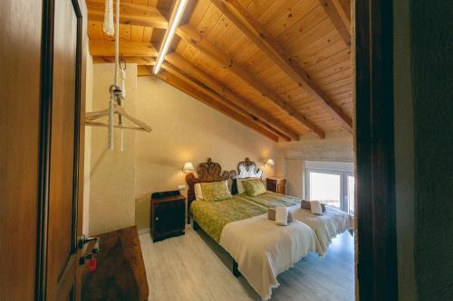 - une chambre avec un lit et un plafond en bois dans l'établissement Las Postas del Perionda, à Calzada de los Molinos