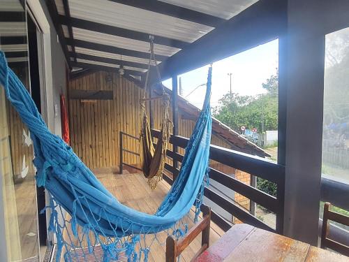 una hamaca azul en una habitación con ventana en Residencial Bombinhas Pé na Areia, en Bombinhas