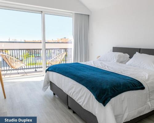 ein Schlafzimmer mit einem großen Bett und einem großen Fenster in der Unterkunft TRIADE Apartamentos in Aveiro