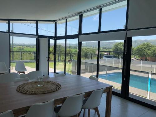 comedor con mesa, sillas y piscina en Olivos del Solar en Villa General Belgrano