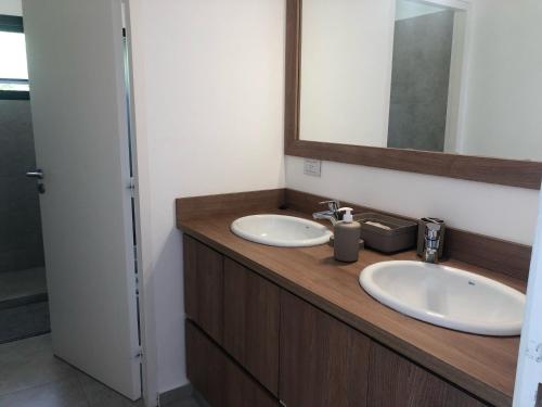 a bathroom with two sinks and a mirror at Olivos del Solar in Villa General Belgrano