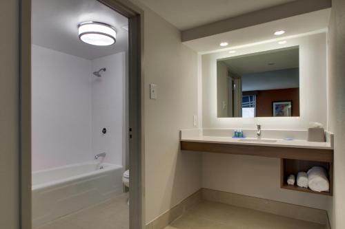 a bathroom with a sink and a tub and a mirror at Holiday Inn Express Voorhees/ Mt. Laurel, an IHG Hotel in Voorhees