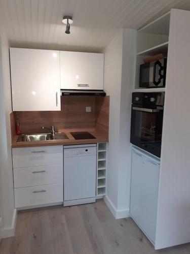une cuisine avec des armoires blanches et un évier dans l'établissement Studio Canapé convertible 2 pers avec jardin et parking clos, à Merlimont