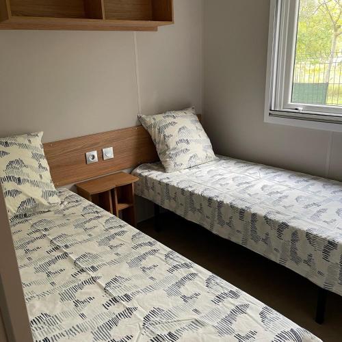 deux lits dans une petite pièce avec une fenêtre dans l'établissement La Carabasse Mobilhome Vias plage, à Vias