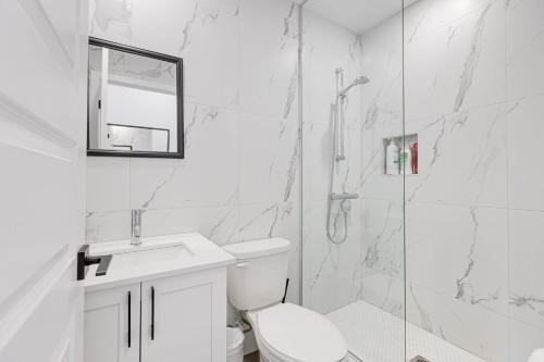 La salle de bains blanche est pourvue d'une douche et de toilettes. dans l'établissement M11 Upscale Spacious 1BR wKingBed AC in Heart of PlateauMile-End, à Montréal