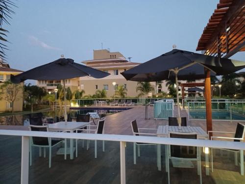 a patio with tables and umbrellas next to a pool at Lindo Flat em resort silencioso e aconchegante in Brasília