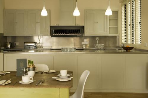 a kitchen with white cabinets and a table with chairs at Brooks Guesthouse Bristol in Bristol
