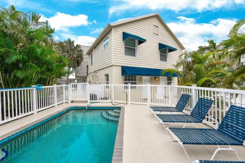 a villa with a swimming pool and two blue chairs at Parrot Beach Cottages in Siesta Key