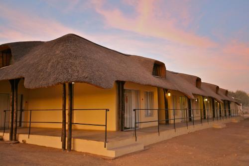 a row of buildings with a thatched roof at Schuetzenhaus Guesthouse in Keetmanshoop