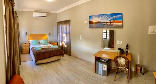 a bedroom with a bed and a desk in a room at Schuetzenhaus Guesthouse in Keetmanshoop
