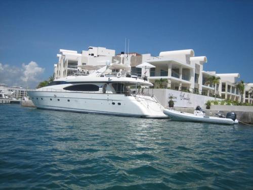 a white boat in the water next to a house at La Amada Residences. Best Stay in Cancún