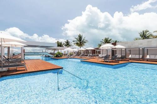 a large swimming pool with chairs and umbrellas at La Amada Residences. Best Stay in Cancún