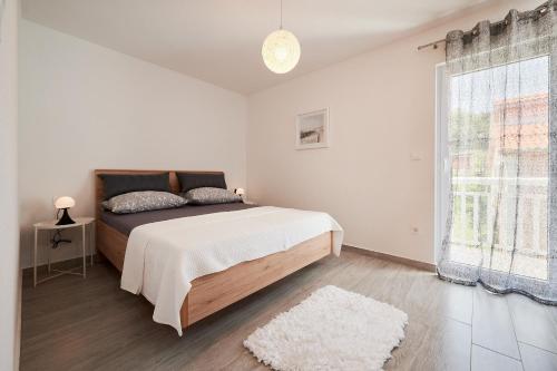 um quarto branco com uma cama e uma janela em Apartment Adrian2 em Trogir