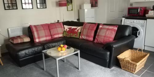 The Stables في Tregaron: أريكة جلدية سوداء في غرفة معيشة مع طاولة