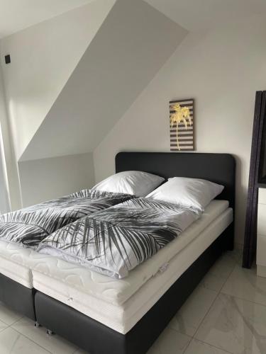a bed with a black and white comforter and pillows at Ferienwohnungen im Palmengarten - 40 qm in Heitersheim