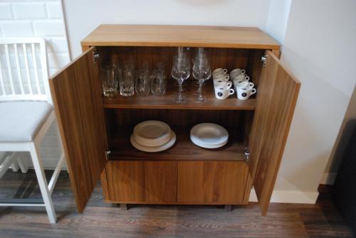 a wooden cabinet with glasses and dishes on it at Altar Suites Conde Luna by gaiarooms in León