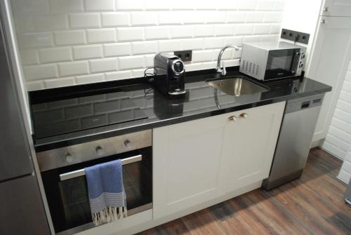 a kitchen with a sink and a counter top at Altar Suites Conde Luna by gaiarooms in León