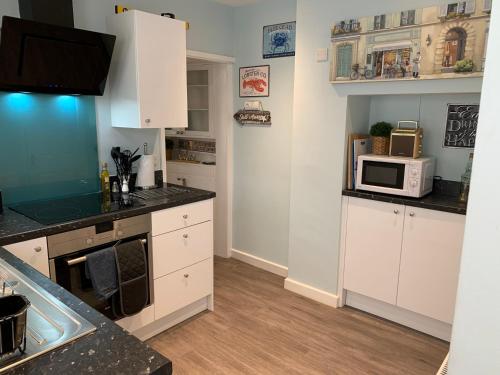 a kitchen with white cabinets and a microwave at Ground Floor Apartment in Exmouth