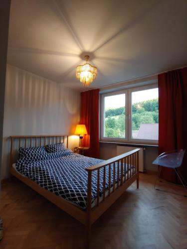 a bedroom with a bed and a window and a chandelier at Apartament u Tomka Premium in Ustrzyki Dolne