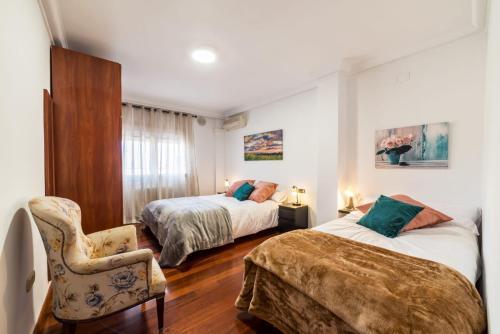 Un dormitorio con 2 camas y una silla. en La Casita de Gracia, en Monachil