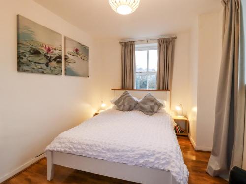 a bedroom with a bed with white sheets and a window at Lair Close Cottage in Birstwith