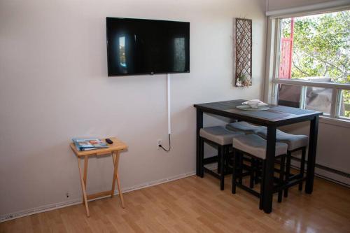 ein Wohnzimmer mit einem Tisch und einem TV an der Wand in der Unterkunft Corail de mer 4 à 2 min de la plage in Sainte-Luce-sur-Mer