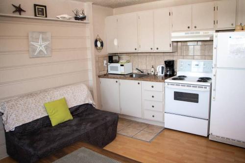 eine Küche mit einem Sofa und einem weißen Kühlschrank in der Unterkunft Corail de mer 4 à 2 min de la plage in Sainte-Luce-sur-Mer