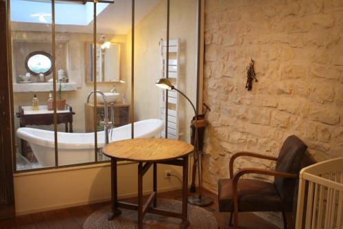 a bathroom with a tub and a table and a chair at My Tasse de Thé in Saint-Maurice-sous-les-Côtes