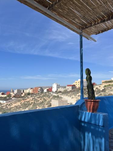 a statue sitting on a blue wall with a view of the ocean at Let Us Surf in Tamraght Ouzdar