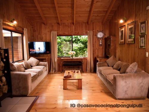 Sala de estar con 2 sofás y mesa en Cabaña Familiar Panguipulli, en Panguipulli