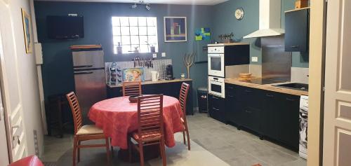 cocina con mesa, sillas y nevera en GITE Appartement 2/3 pers., en Bordères-sur-lʼÉchez