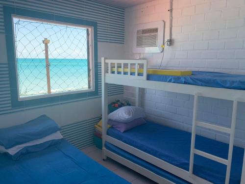 a room with two bunk beds and a window at Paraíso Pé na Areia em Maragogi in Maragogi