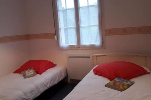 a bedroom with two beds with red pillows and a window at Gite Le Titou entre terre et mer in Puys