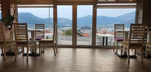 a dining room with a table and chairs and windows at Hotel Rivero A&S in Mostar