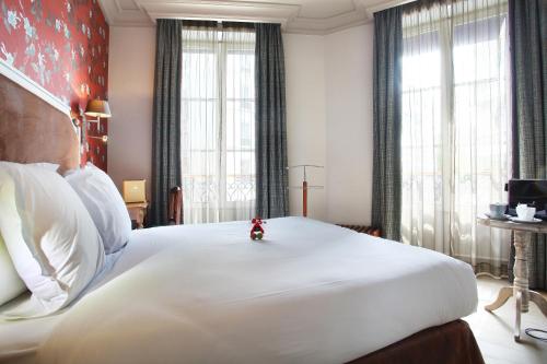 een groot wit bed in een kamer met ramen bij Le Robinet d'Or in Parijs