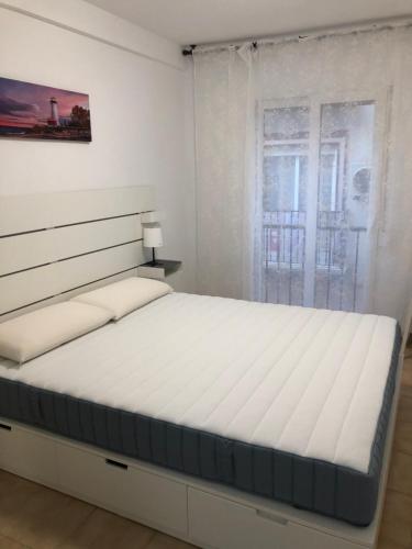 a white bedroom with a large bed in front of a window at Sant Vicent 35 in heart of Old town in Benidorm